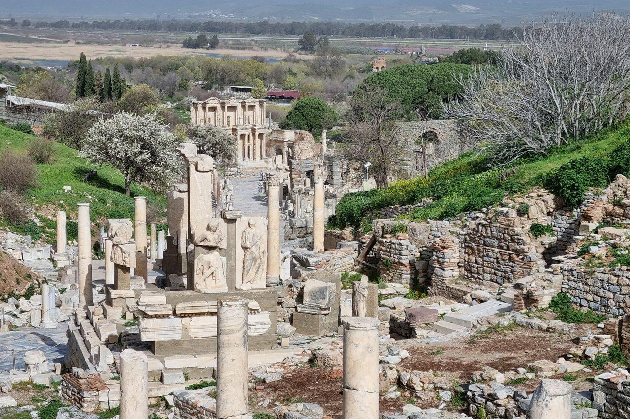 Marble columns, paving and ruined façades of the ancient city of Ephesus under clear sky.